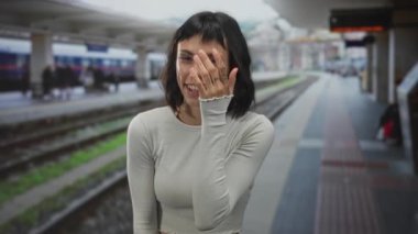 Tren istasyonunda göğüs göğüse gülen kadın hafif bir kazak giyiyor, kaygısız bir mutluluk..