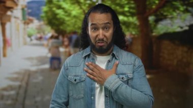 Sokakta ağaçlar ve bulanık yayalarla göğüs göğüse kot ceket giyen adam samimi bir özür diliyor..