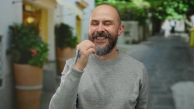 Sakallı ve dövmeli, şehir dışında gri süveter giyen, mutluluğu ifade eden bir adam..