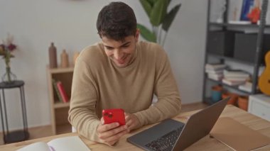 Erkek akıllı telefonu kapar ve evde kutlama yapar. Genç bir İspanyol erkek kapalı bir video görüşmesi sırasında cep telefonunu kaldırır..