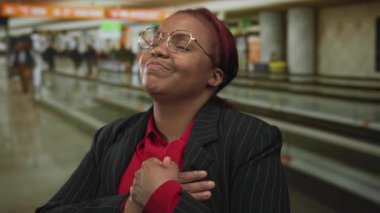 Havaalanı terminalinde çizgili takım elbiseli ve gözlüklü bir kadın..