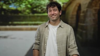 Gülümseyen adam, tarihi mimarisi ve yemyeşil zeminiyle pitoresk bir Akdeniz kasabasında neşeli tavırlarını vurgulayan büyüleyici bir zemin hazırlıyor.