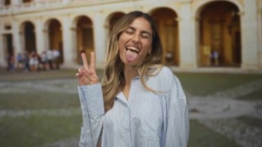 Roma avlusunda iki parmak barış işareti gösteren ve dillerini kemer yolları ve kaldırım taşı plazasıyla dışarı çıkaran bir kadın..