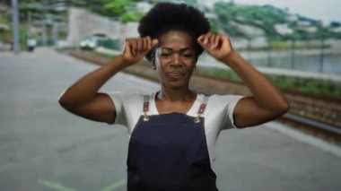 Tren istasyonunda önlükle esneyen bir kadın, açık hava tren ayarlarına güvenerek gelen bir trenin beklentisini sembolize ediyor..