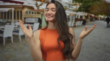 İspanyol kadın geniş bir gülümseme ve açık avuçlar ile ellerini kaldırıyor açık restoran terasında; saf neşe.