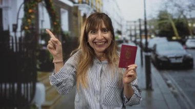 Pasaportlu ve sağ işaret parmağıyla şehir caddesinde park halindeki arabaların ve demir kapıların yakınını gösteren kadın. Sürpriz seyahat macerası..