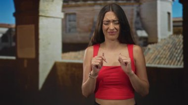 Kırmızılı kadın avuçları açık ve parmakları taştan yapılar halinde eski kasaba caddesinde serili. Tiksinti tereddüt reddediyor..