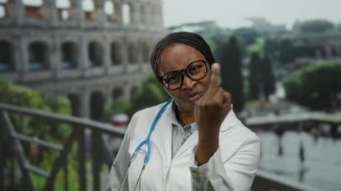 Roma Kolezyumu 'nun yanında gözlüklü kadın doktor. Roma' da steteskop ve beyaz önlük giymiş düşünceli görünüyor..