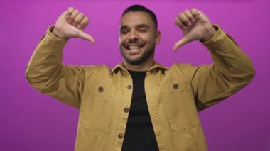 Stüdyo ortamında çift başparmak aşağı hareket gösterirken sarı tişört giyen bir adamın ön görünümü;.