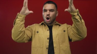 Sarı ceket giyen İspanyol genç adam kırmızı stüdyoda elini kaldırdı ve ağzını açtı..