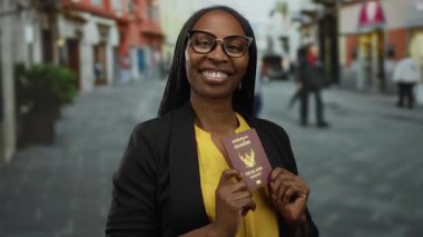 Arka planda dükkanlar olan bir caddede elinde Tayland pasaportuyla gülümseyen bir kadın..