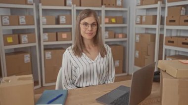 Sarışın kadın bina içinde paket ve laptop ile ahşap masanın üzerinde dinleniyor; huzur verimlilik organizasyonu.