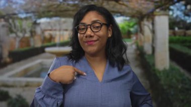 Kadın gülümser ve kendini bir binaya mermer sütunlarla çerçevelenmiş taş bir çeşmenin yanında gösterir..