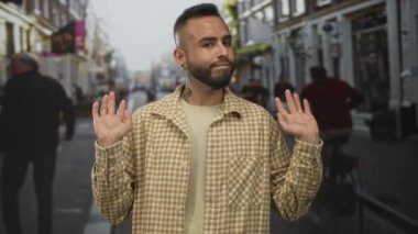 Avuç içleri kalkık ve şehir caddesinde görünen yüzükleri olan, boynu dövmeli ve tarafsız bir ifade takınan, ilgisiz bir adam..