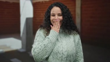 Bir inşaat alanında kapalı alanda gülümseyen süveter giyen genç İspanyol kadın neşeli bir ifade ve rahat bir tavır sergiliyor..