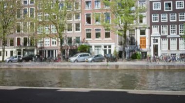 Güneşli bir günde Amsterdam 'daki eski binalar ve kanallar bulanıktı. Bisikletler, park halindeki arabalar, su yolu ve yeşil ağaçlar manzaralı sokaklara eklendi..