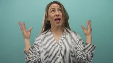 Turkuaz stüdyoda elleri konuşan sarışın kadın; iletişim dışavurumculuğu hüsranı vurguluyor.