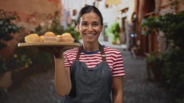 Bir kaldırılmış el kaldırılmış ahşap muffin tepsisi taşıyan kadın kaldırım taşı sokak pazarında; konukseverlik küçük işletme.