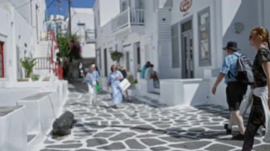 Yumuşak Bokeh caddesinde beyazlatılmış binaları, desenli taş kaldırımları, dar sokakları ve balkonları gösteren odaksız Mykonos sahnesi; arka plan telif alanı.