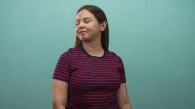 Nane yeşili stüdyodaki kameraya uzanan, çizgili üst kısmı görünür, kendine güveni olan bir kadın işaret ediyor..