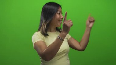 Stüdyoda her iki işaret parmağı da canlı yeşil ekran, gülücük ve jest ortası mutluluk nişanı karşısında sağa dönük..