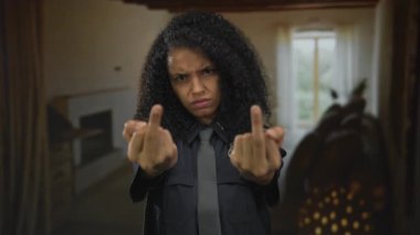 Genç İspanyol polis memuru odada çatık kaşlı çifte orta parmak hareketi gösteriyor..