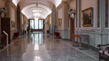 Sığ bir bokeh, mermer zemin, avizeler, çerçeveli tablolar ve ahşap bir masa ile bir müzede hafif odaklanmış koridor; arka plan fotokopi alanı.