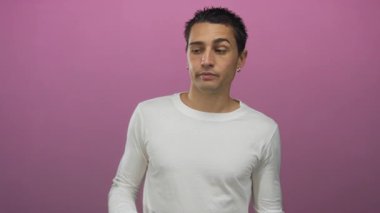 İzole edilmiş pembe arka plana karşı beyaz tişört giyen İspanyol genç adam.