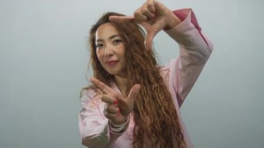 Stüdyoda elleri soluk mavi arkaplan karşısında pembe gömlek ve bilezikler giyen, yaratıcı oyuncu bir kadın..