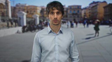 Açık mavi gömlekli genç adam tarihi binanın yanındaki kalabalık caddede elleri ile ağzını kapatıyor. Sürpriz!.