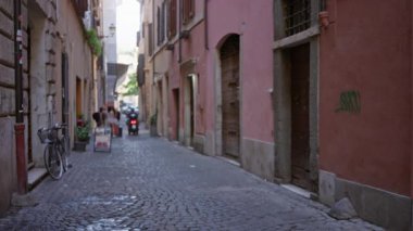 Dar Roma caddesi kaldırım taşı kaldırımlı ve sessiz pastel cepheli yumuşak odaklı bokeh; arka plan arka plan telif alanı sakin.