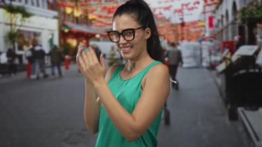 Caddede yeşil bir tankta tırnaklarını yiyen gözlüklü bir kadın; utangaçlık ve alçakgönüllülük..