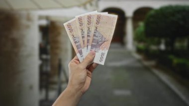 İzlanda Krona banknotları tutan bir adam, şehir merkezinde gündüz vakti para birimini açık havada gösteren beyaz elle finans kavramını resmediyor..