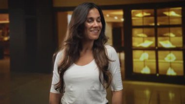 Kadın gülümserken ve yan bakarken mağazadaki mücevher vitrinini işaret ediyor; sürpriz keşif.