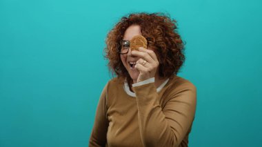 Mavi arka planda mutlu bir ifadeyle kurabiyeyi tutan kadın orta yaşlı, İspanyol bir kadının tecrit ortamında atıştırmalık yemesinin keyfini çıkarıyor..