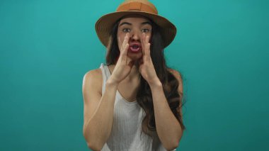 Stüdyoda bağıran, hasır şapka takan ve beyaz askılı fincanlar takan genç bir kadın..