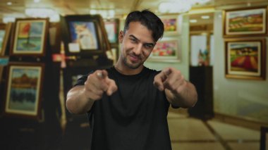 Bir sanat galerisindeki genç adam coşkuyla canlı tabloların arasında, bağlılık ve neşe hissi ile canlı bir iç mekan atmosferi yaratıyor..