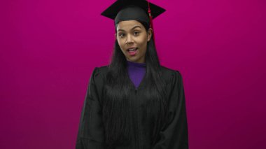 Havan paneli ve bornozlu kadın usulca gülümser ve pembe bir stüdyoda güven içinde poz verir..