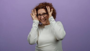 Gözlüklerle gülümseyen bir kadın, pembe arka planda neşeli bir ifadeyle, gizli yüzden neşeli bir yüze, orta yaşlı esmer bir kadına duygularını gösteriyor..