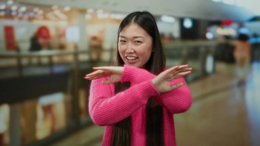 Pembe kazaklı kadın hareketli bir alışveriş merkezinde, modern bir alışveriş merkezinde Asyalı güzellik ve cazibesini sergiliyor..