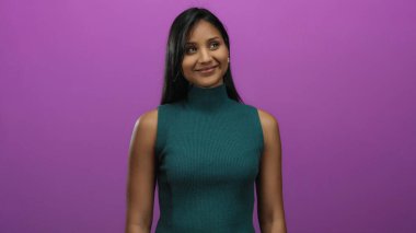 Yeşil bluzlu gülümseyen kadın canlı pembe arka plana karşı duruyor, neşeli ve modern bir portre için mutluluğu ve sadeliği kucaklıyor..