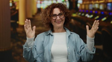 Kumarhanede arka planda kumar makineleri olan bir kadın neşeli bir oyun atmosferi yakalıyor..