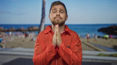 Turuncu tulumlu, elinde palmiyeler, sahil kenarında palmiye ağacının altında dua eden, vicdan azabı çeken genç bir mahkum..