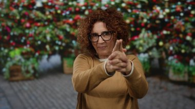 Bir kadın, açık hava dükkanında canlı çiçeklerin önünde, renkli bir botanik piyasasında anlamlı ve eğlenceli bir an sergiliyor..