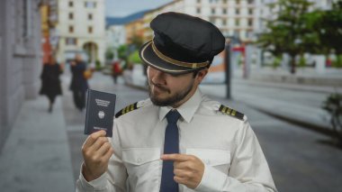 Üniformalı genç bir pilot elinde Alman pasaportuyla bir sokakta, şehir arka planına karşı profesyonel bir tavır sergiliyor..