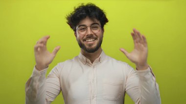 Başarıyı kutlayan genç adam gözleri kapalı ve yumrukları parlak sarı bir arkaplanda, mutluluk ve zaferi ifade ediyor..