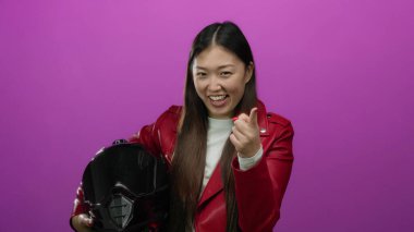 Kırmızı ceketli bir kadın canlı pembe arka plana karşı kaskını tutuyor modern tarz ve enerji gösterisi yapıyor.