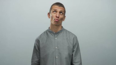 Gri gömlekli bir adam beyaz bir duvara karşı çeşitli duygular besliyordu. Tarafsız bir arkaplan ile izole edilmiş bir stüdyoda yüz ifadelerini vurguluyordu..