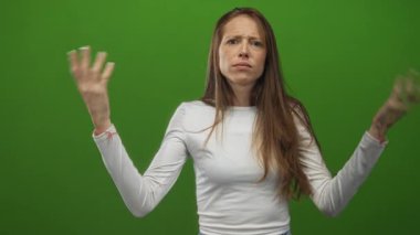 Avuçlarını silkerek yeşil stüdyo ortamında ellerini açık gösteren İspanyol bir kadın..