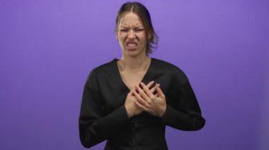 Mor stüdyoda elleri göğsüne yapışan genç İspanyol kadın kalp krizinden sonra siyah giyiniyor..